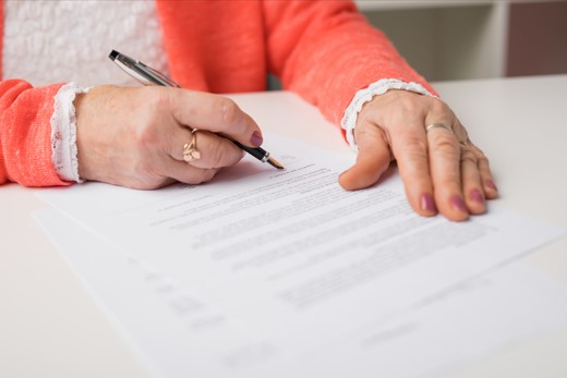 elderly woman signing estate planning paperwork